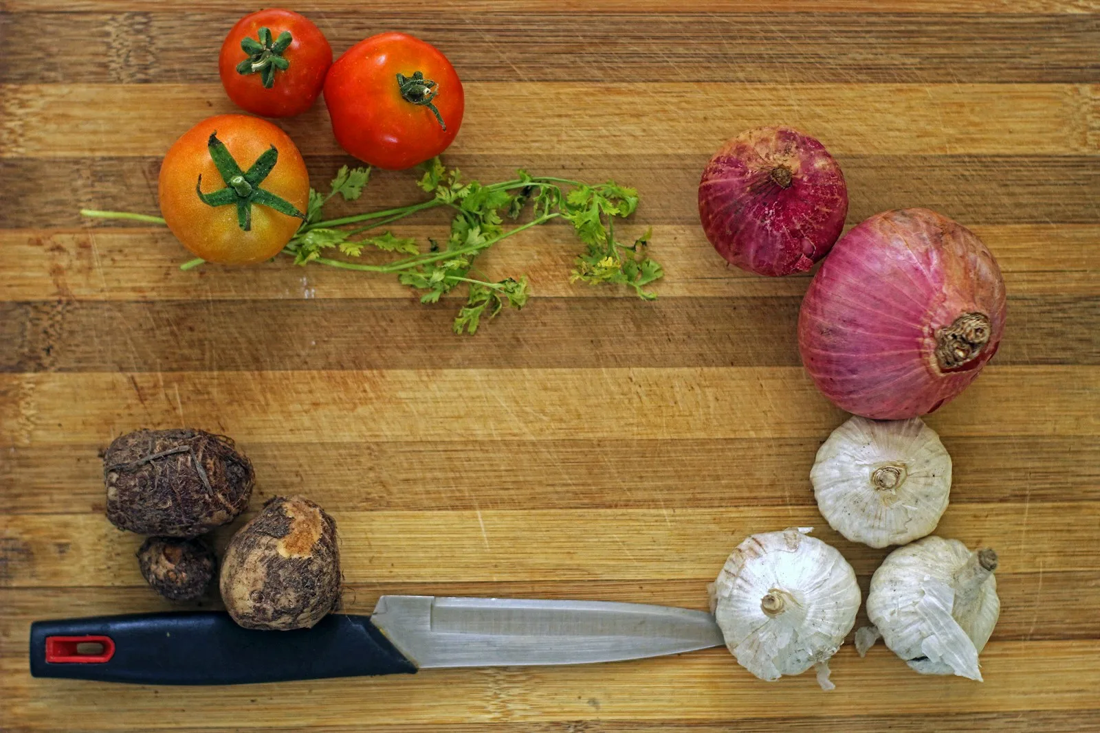 Tomaten, ui en knoflook op een snijplank als ingrediënten voor tomatensaus
